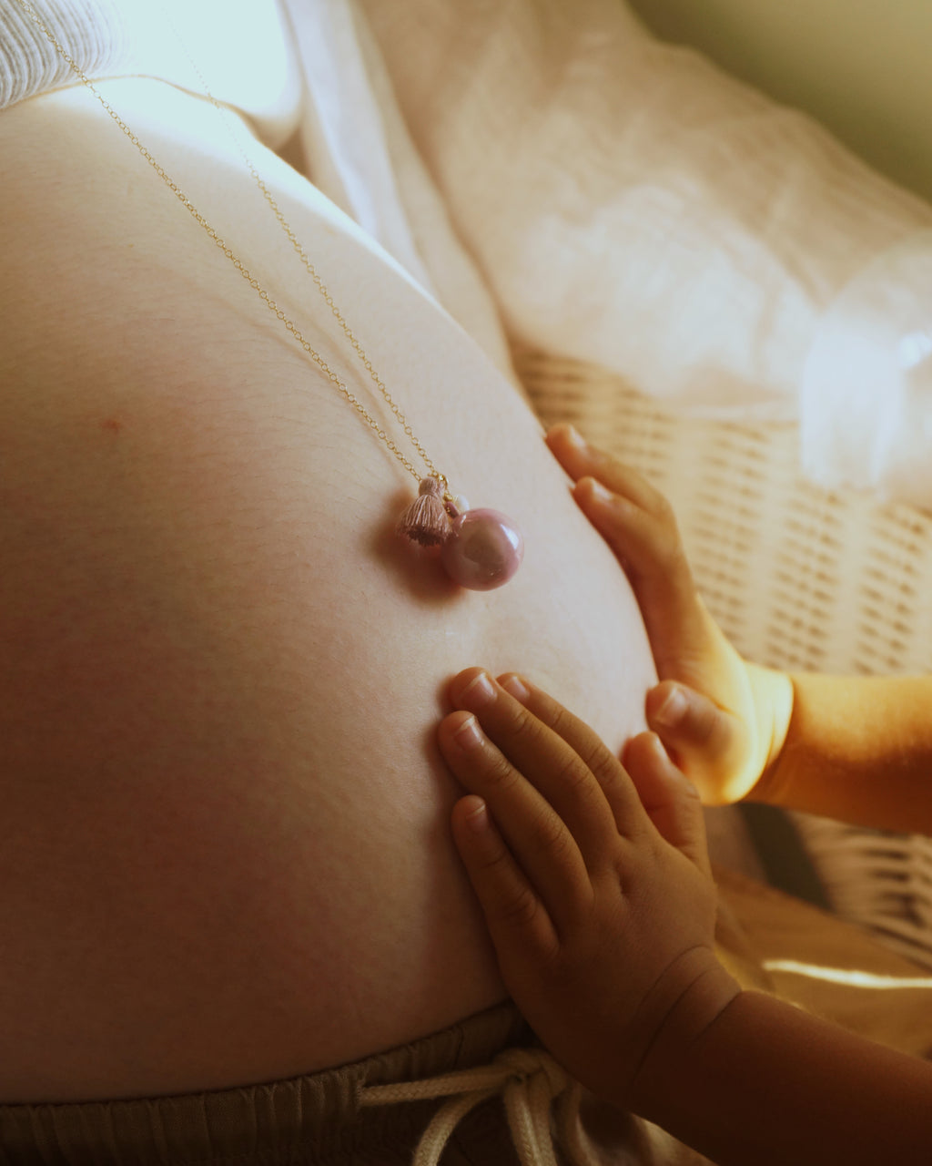 妊婦の女性がBo-emeブランドのマタニティネックレスを身につけ、赤ちゃんの小さな手が優しくお腹に触れる写真。胎教、安産祈願（anzan no omamori）、妊娠中のリラックス、プレママアクセサリー、ベビーシャワーギフト、妊婦ファッション、ヨガ・プレナタル、赤ちゃんをお腹で感じる方法など、妊娠期のさまざまなテーマに対応した画像です。妊娠中のスキンケアや栄養管理、出産準備を進める妊婦の生活には、マタニティウェアや妊婦帯、妊婦マークや母子健康手帳が欠かせません。胎教や安産祈願のために、胎教ネックレス、安産祈願ネックレス、お守りネックレスを身につけ、ガムランボールやハーモニーボールで穏やかな胎動を感じましょう。